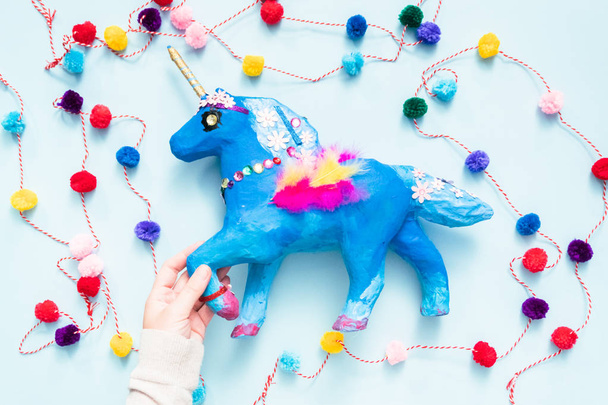 Kids craft. Painted blue and decorated with jewels and feathers paper mache unicorn. - Photo, Image