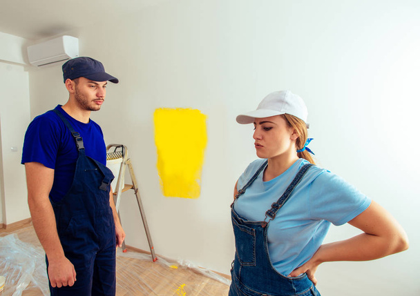Beautiful couple is resting from painting wall in yellow in their new apartment - Photo, Image