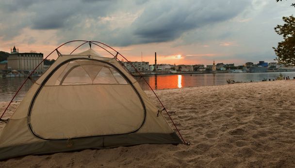 Egy sátor, a turisták található, kilátással a nyári partra a lenyugvó nap sugaraiban, Kijev city beach. - Fotó, kép