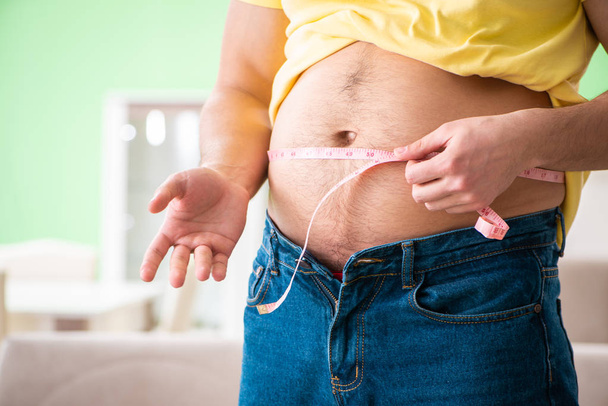 Чоловік вимірює жир стрічкою в концепції дієти
 - Фото, зображення