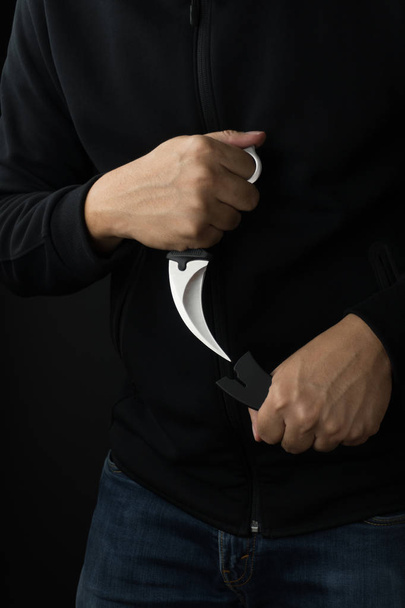 Kampf- und Gewaltkonzept, ein Mann zückt ein Karambitmesser - Foto, Bild