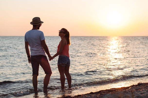 Fiatal pár élvezi a naplementét a strandon szerelmes - Fotó, kép