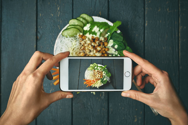 woman taking pictures phobuddha bowl with vegan food, fried chickpeas, rice noodles with wegetables - Fotó, kép