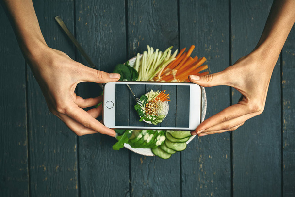 woman taking pictures phobuddha bowl with vegan food, fried chickpeas, rice noodles with wegetables - Fotó, kép