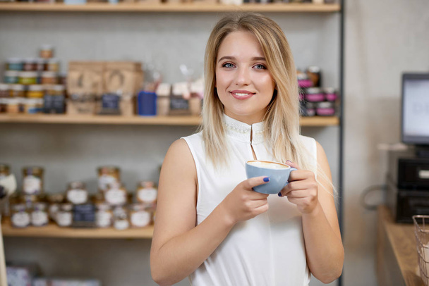 Portrait of smiling girl keeping cup of coffee , looking at camera. - 写真・画像