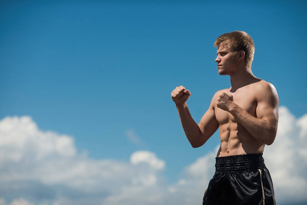 A man is a fighter in the fighting rack on sky backround - 写真・画像