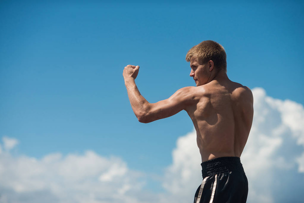 Muscular male fighter training on sky backround. Boxer trains in the open air - Foto, Imagem