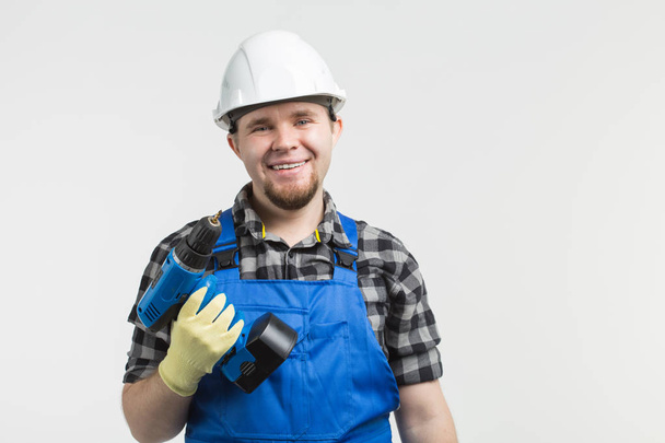 Happy builder standing with screwdriver on white background - Foto, Imagen