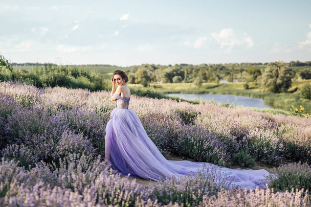 hermosa mujer joven en vestido largo morado de pie posando en el campo de lavanda, longitud completa
 - Foto, imagen
