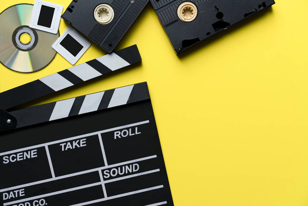 映画クラッパー、cd、ビデオ カセット テープ黄色テーブル上映画、映画館、ビデオの撮影コンセプト - 写真・画像