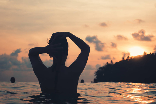 Молодая женщина сзади в Индийском океане купается и держит ее
  - Фото, изображение