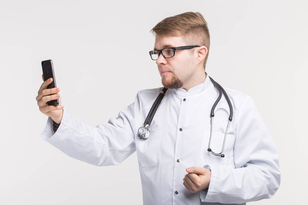 Young male doctor making photo on his phone - Zdjęcie, obraz