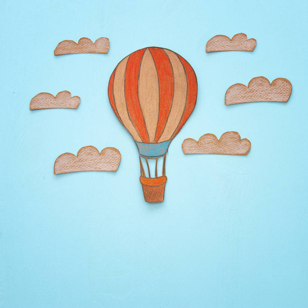 Hot air balloon, space elements shapes cut from paper and painted over wooden blue background - Foto, Bild
