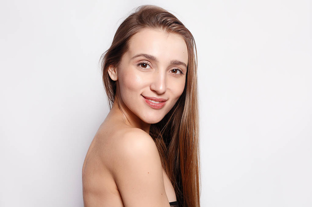 fashion, people, youth and beauty concept - Beautiful smiling woman with natural make-up, clean skin and white teeth on grey background. Beauty portrait of female face with natural skin - 写真・画像