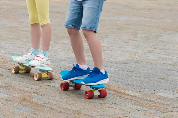 children boy and girl ride skateboards on a city street - Fotoğraf, Görsel