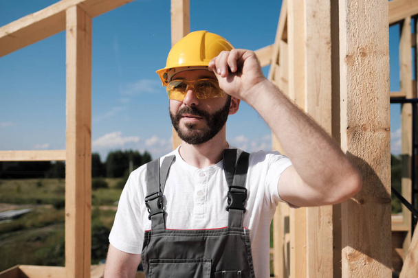 The man is a builder on the roof of a wooden frame house. - 写真・画像