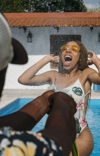Latin woman with yellow glasses plays with water in pool - Fotografie, Obrázek