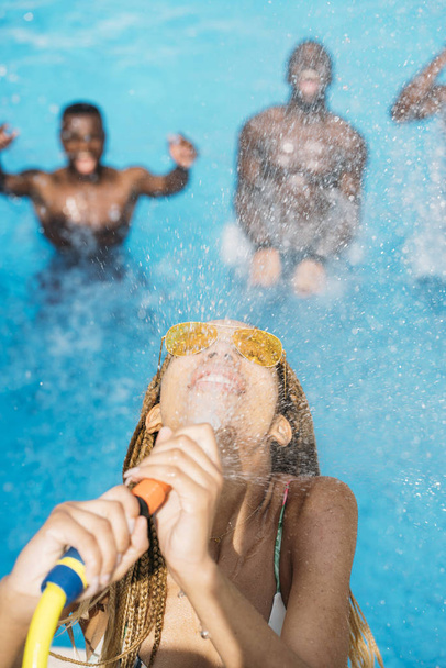 Латинская женщина в желтых очках играет с водой в бассейне
 - Фото, изображение