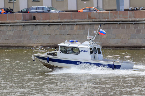 Moscow, Oroszország - 2018. június 21.: Rendőrségi hajó rohanó víz felszínén, szemben a Moszkva folyó töltésén, egy napsütéses nyári napon - Fotó, kép