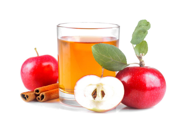 Piękne dojrzałe świeże czerwone jabłko z zielonych liści i sok jabłkowy, obok cynamon na na białym tle - Zdjęcie, obraz