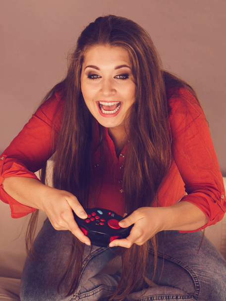 Nerd geek young adult women playing on the video console holding game pad sitting on sofa. Gaming gamers concept. - Fotó, kép