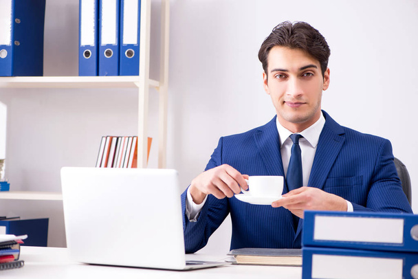 Молодой привлекательный бизнесмен, работающий в офисе за столом - Фото, изображение