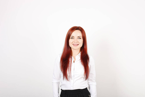 Positive beautiful businesswoman wearing formal wear, black skirt & white blouse standing & smiling. Attractive redhead woman with red hair and make up. Isolated white background, copy space, close up - Photo, image