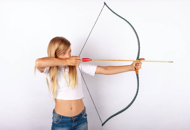 Young archer girl targeting with bow and arrow - Zdjęcie, obraz