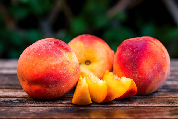 Fresh ripe peaches and slices on wooden table - Foto, Imagen