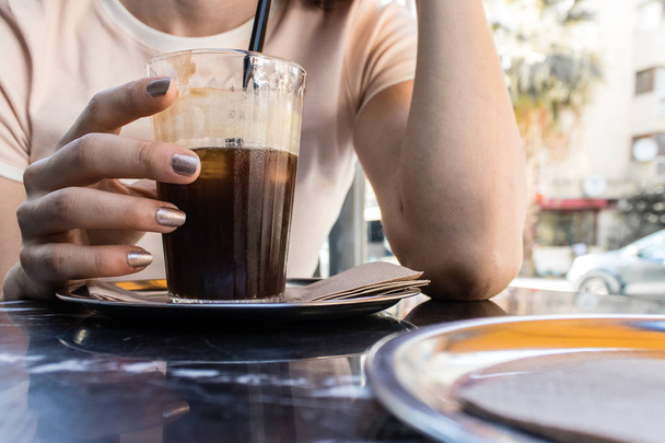 Dziewczyna, picie zimnej kawy podczas rozmowy w gorący letni dzień. Zdjęcie pochodzi z izmir, Turcja. - Zdjęcie, obraz