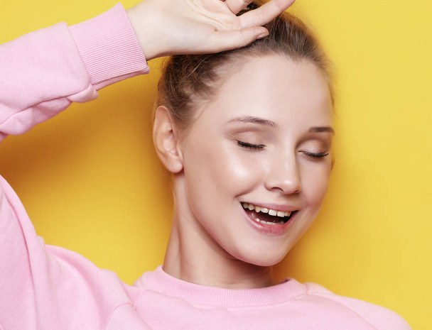 Young blond woman with closed eyes, over yellow background - Valokuva, kuva