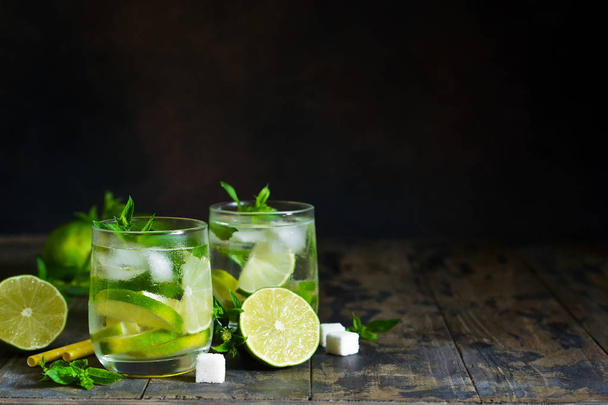Cold alcohol mahito with mint and lime on a dark background. Summer drink. - Фото, изображение