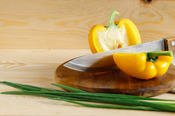 Sliced fresh yellow onion on cutting board with organic green onion. Wooden background - Foto, imagen