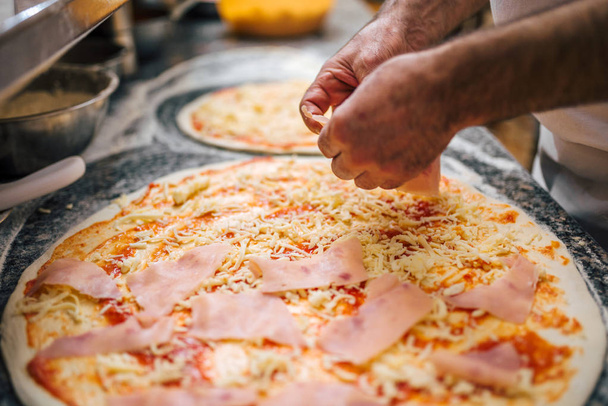 Close-up image of chef adding ingredients on the pizza. - Foto, Bild