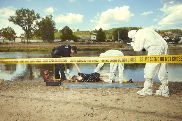 Woman body in black apparel found drowned near summer river bank in city - Foto, imagen