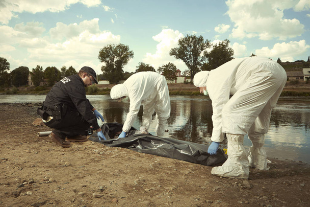 Femme trouvée noyée sur la rive de la rivière dans une ville placée dans un sac mortuaire pour le transport
 - Photo, image