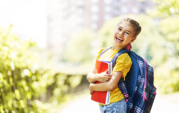 Pupil of primary school with book in hand. Girl with backpack near building outdoors. Beginning of lessons. First day of fall. - Φωτογραφία, εικόνα