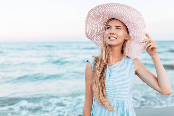 Beautiful portrait of a girl in a hat close-up, rest on the sea or ocean, a woman in a summer blue dress - Foto, afbeelding