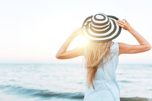 Meisje op zoek in de verte, tegen de blauwe zee, de sfeer van de zomer, de vrouw in de hoed, zonlicht - Foto, afbeelding