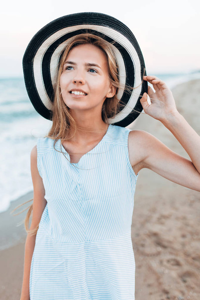 Beautiful portrait of a girl in a hat close-up, rest on the sea or ocean, a woman in a summer blue dress - Фото, изображение