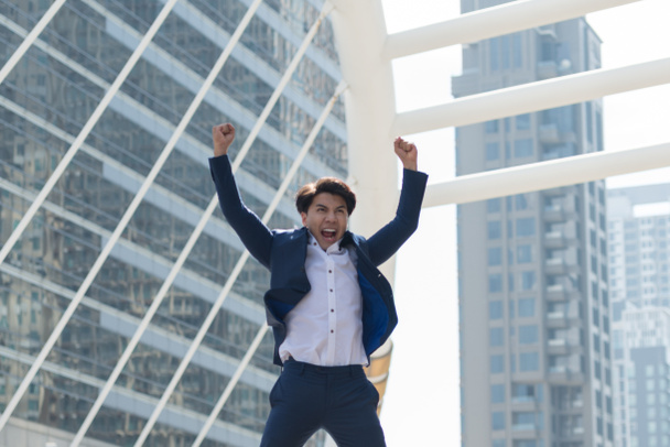 Successful businessman in suit.  He is glad and jumping background in big city. Business concept, Lifestyle concept - Photo, Image