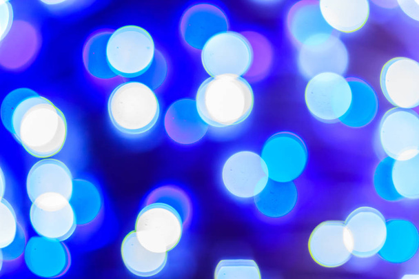 Beautiful blue bokeh abstract light background. Wonderful Defocused abstract blue christmas background. Abstract christmas lights as background in the night with noise grain and poor light. - Фото, изображение