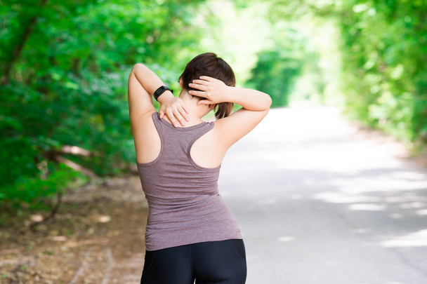 Woman with back pain, neck injury, trauma during workout, outdoors concept - Photo, Image