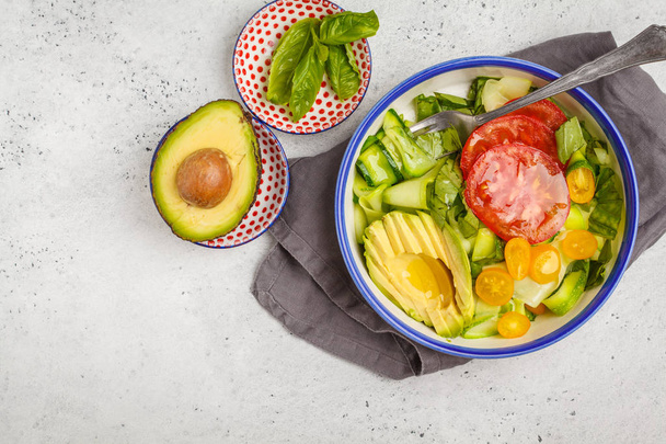 Green zucchini noodles salad with tomatoes, avocado and basil, top view, copy space. Healthy vegan zucchini pasta. Clean eating concept. - Fotó, kép