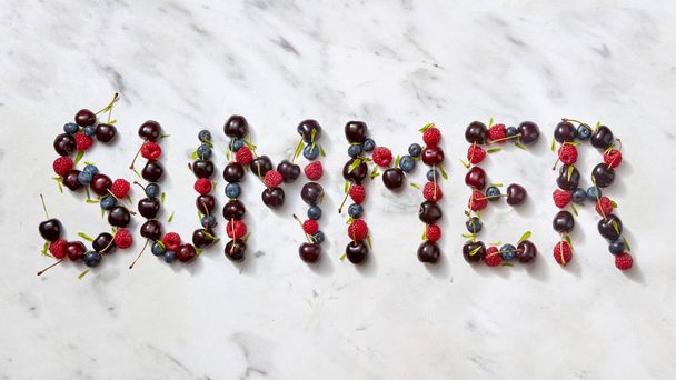 Word SUMMER made ripe sweet juicy red berries on gray stone background. Summer concept of healthy organic rood. Flat lay. - Foto, Bild