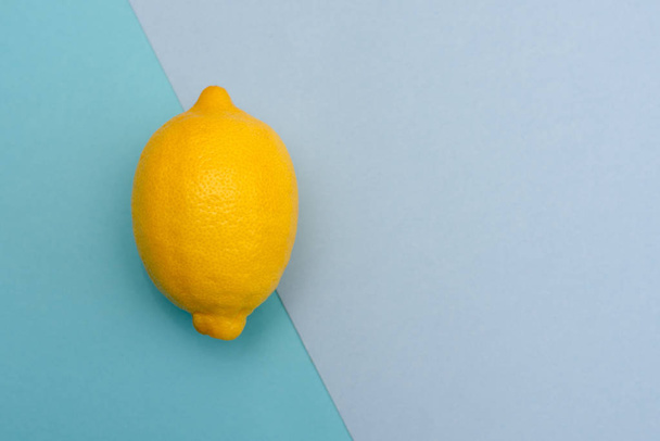 One yellow lemon on a blue background of different shades. The view from the top. - Photo, Image