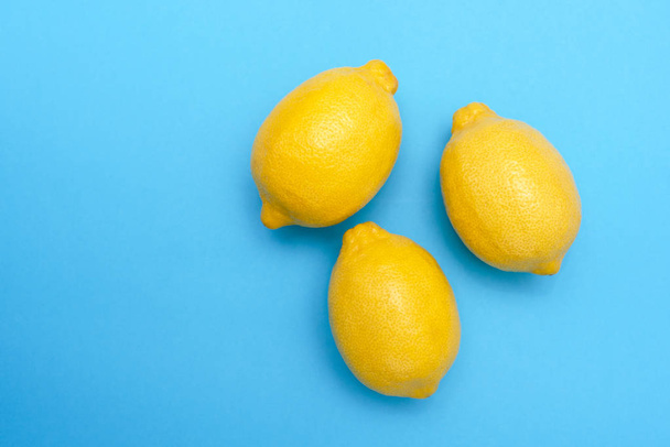 drei gelbe Zitronen auf blauer Oberfläche - Foto, Bild