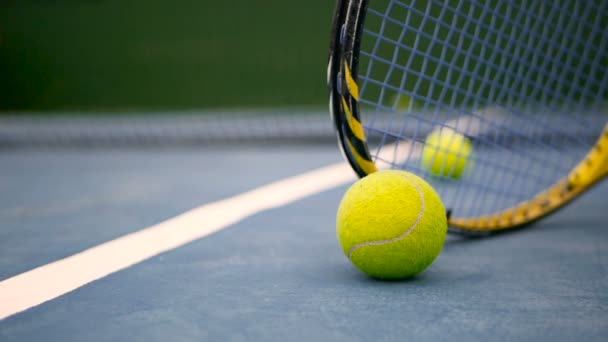 Close up of tennis equipment on the court. Sport, recreation concept. Yellow racket with a tennis ball in motion on a clay green blue court next to the white line with copy space and soft focus. - Footage, Video