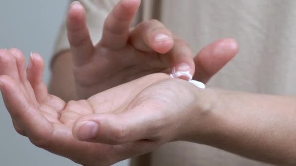 eine Nahaufnahme der Hände einer Frau, die Creme am Handgelenk testet. sie legt einen Tropfen auf das linke Handgelenk und reibt ihn in die Haut. - Filmmaterial, Video