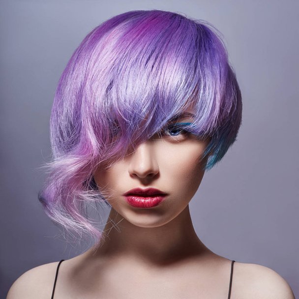 Portrait of a woman with bright colored flying hair, all shades of purple. Hair coloring, beautiful lips and makeup. Hair fluttering in the wind. Sexy girl with short hair - Foto, immagini